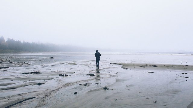 Hooded figure foggy mudflat